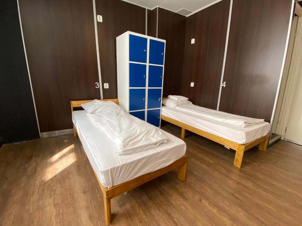 Two made-up single beds either side of a blue locker unit