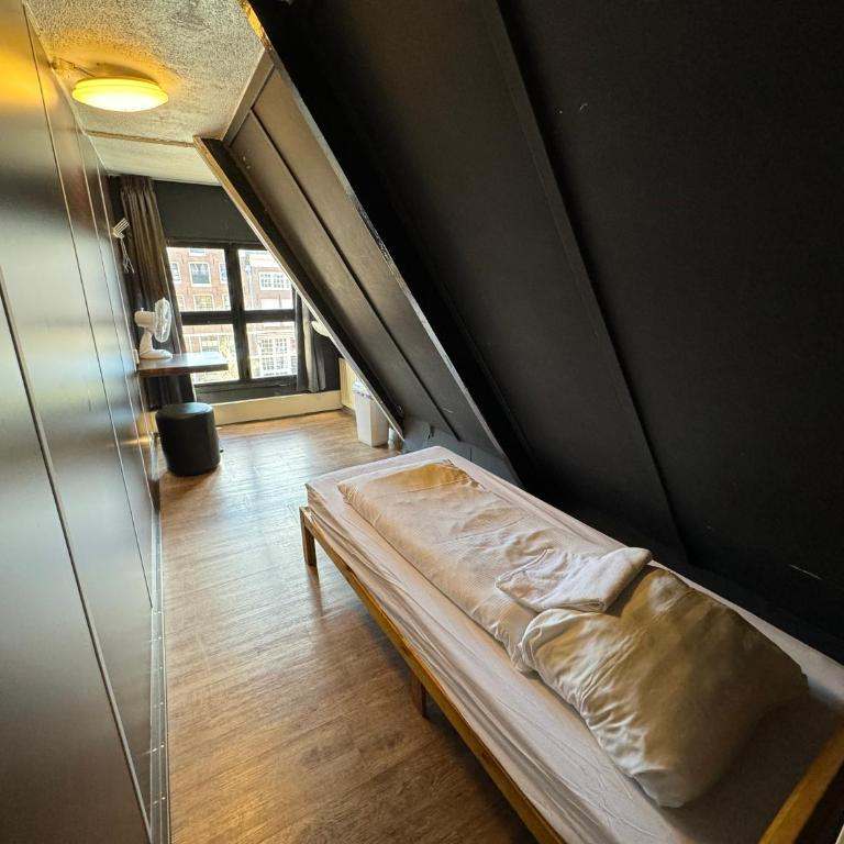 Single bed in a narrow attic room with a window at the end