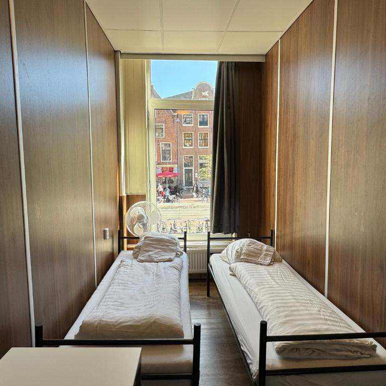 Two single beds in a wood-panelled room with a tall window onto the street