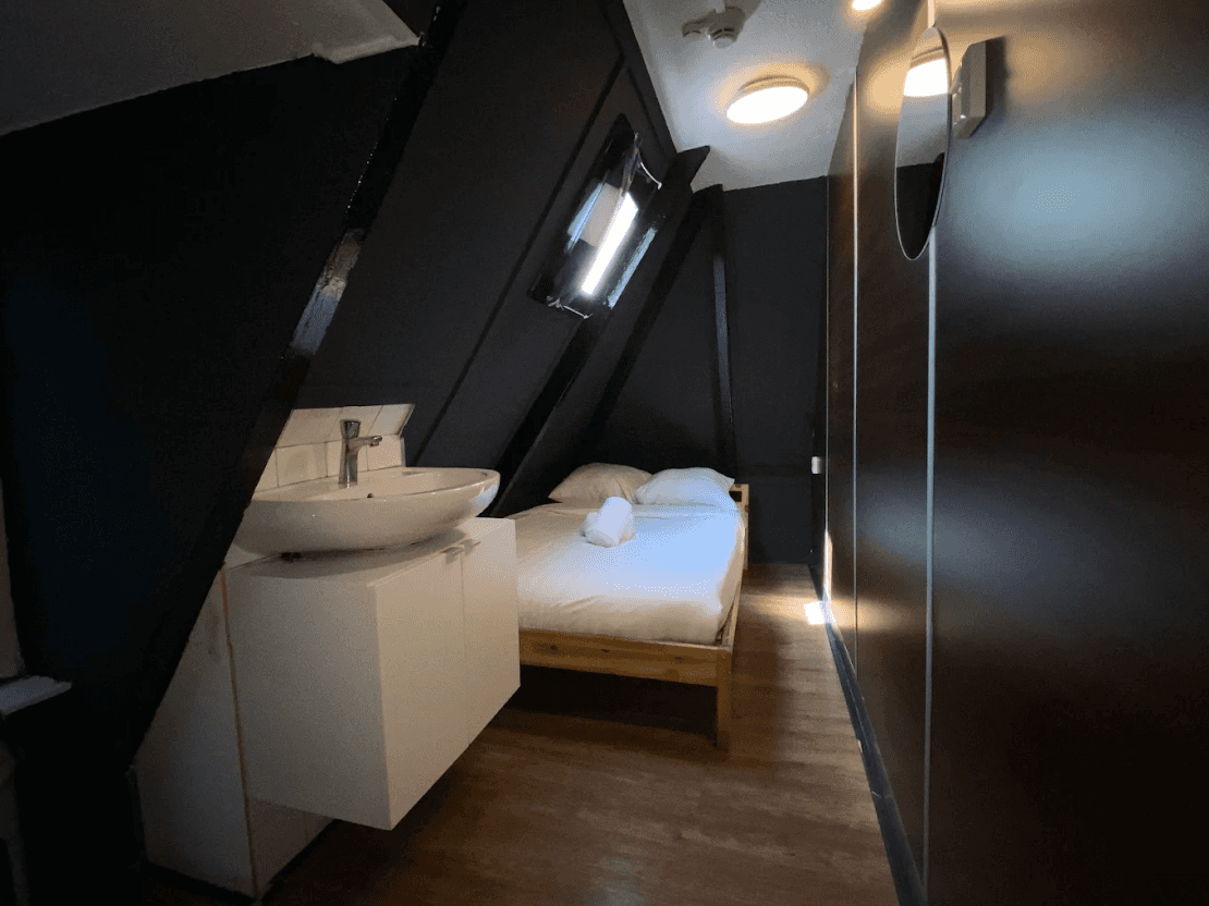 Attic room under a sloping ceiling with a single bed and a washbasin