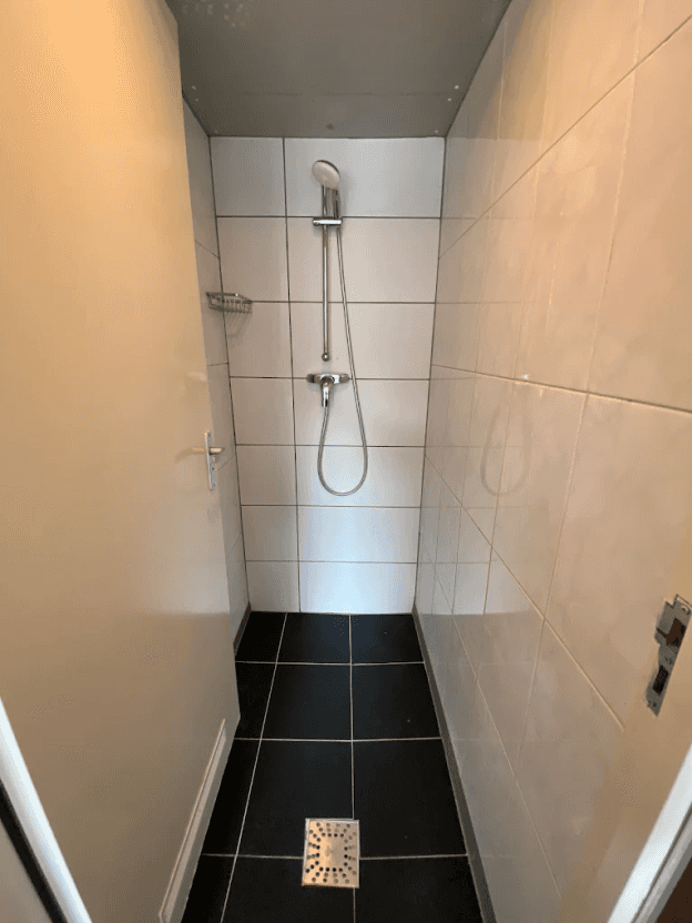 Clean tiled shower cubicle with a handheld shower