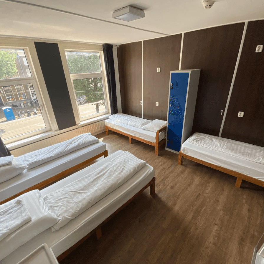 Bright room with four single beds, a blue locker and large windows