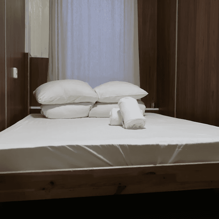 Double bed with white linen and rolled towels in a wood-panelled room